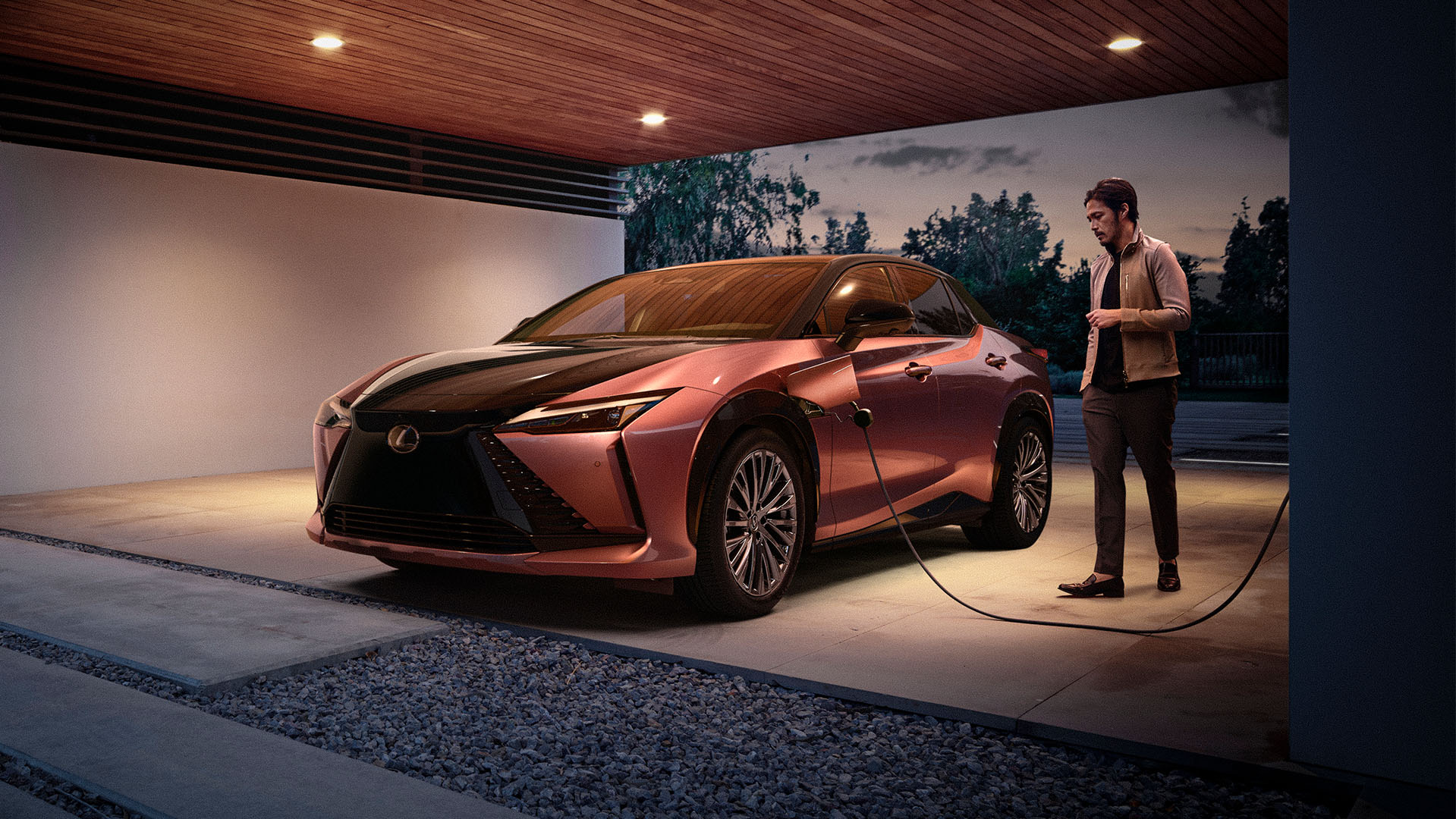 a man plugging a Lexus RZ 450e into a home charging station