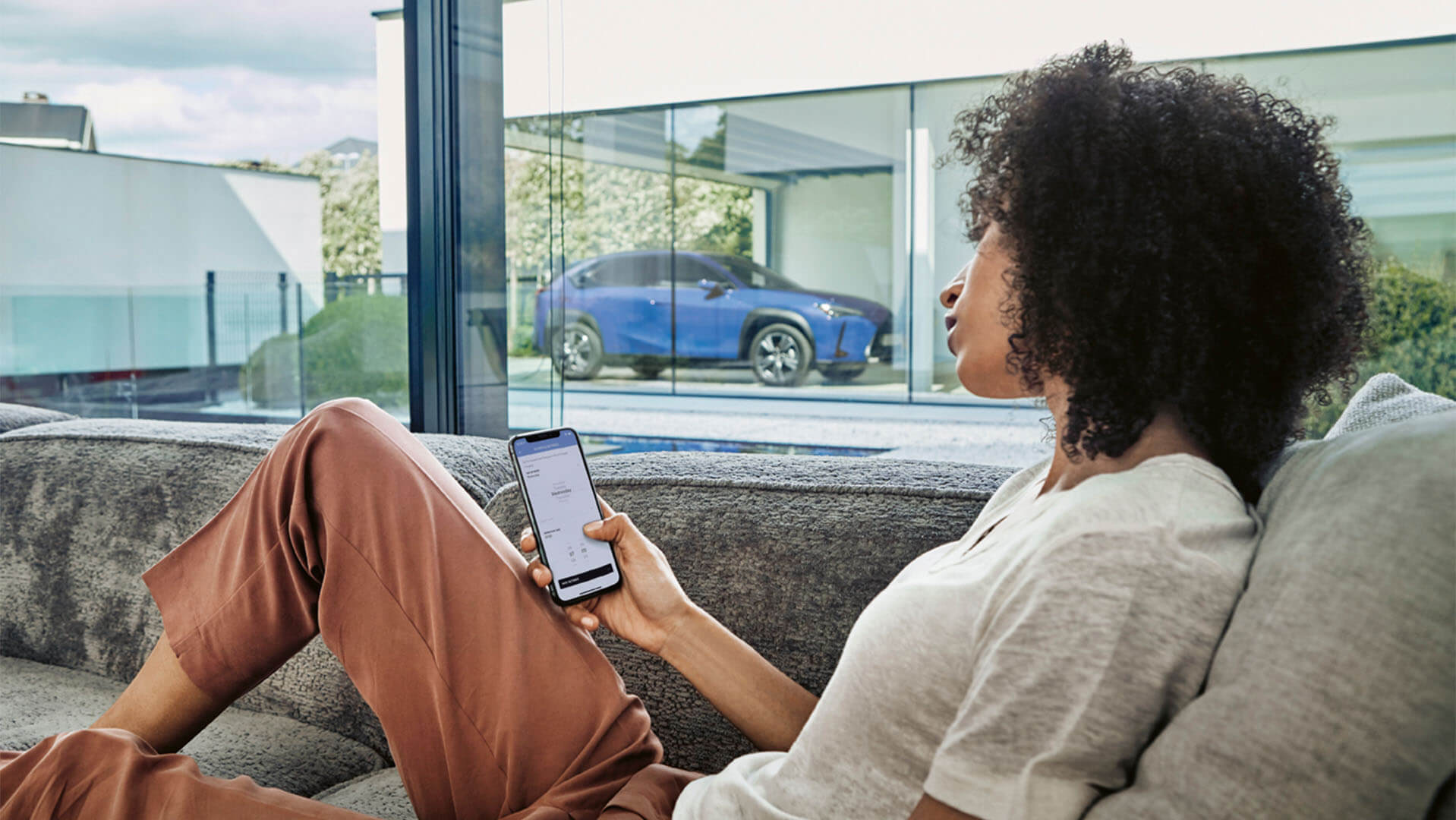 A woman using the Lexus Link app with a Lexus UX 300e in the background 