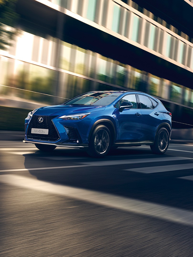 A blue Lexus UX driving in a city location